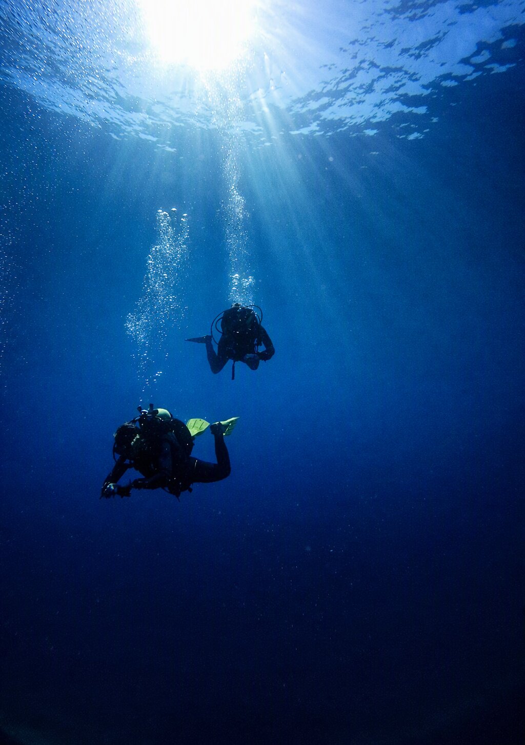 Divers silhouetted against the sun above a Maltese wreck
